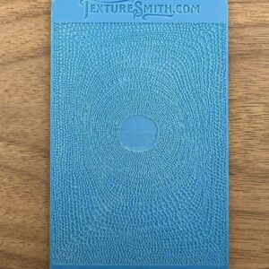 Blue hardcover book with an embossed circular design on a wooden surface.
