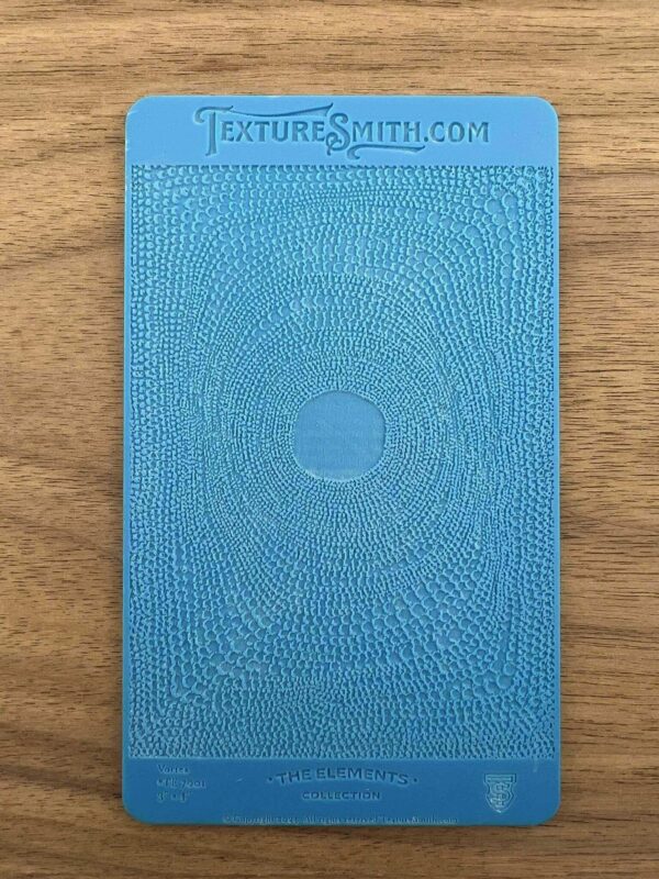 Blue hardcover book with an embossed circular design on a wooden surface.