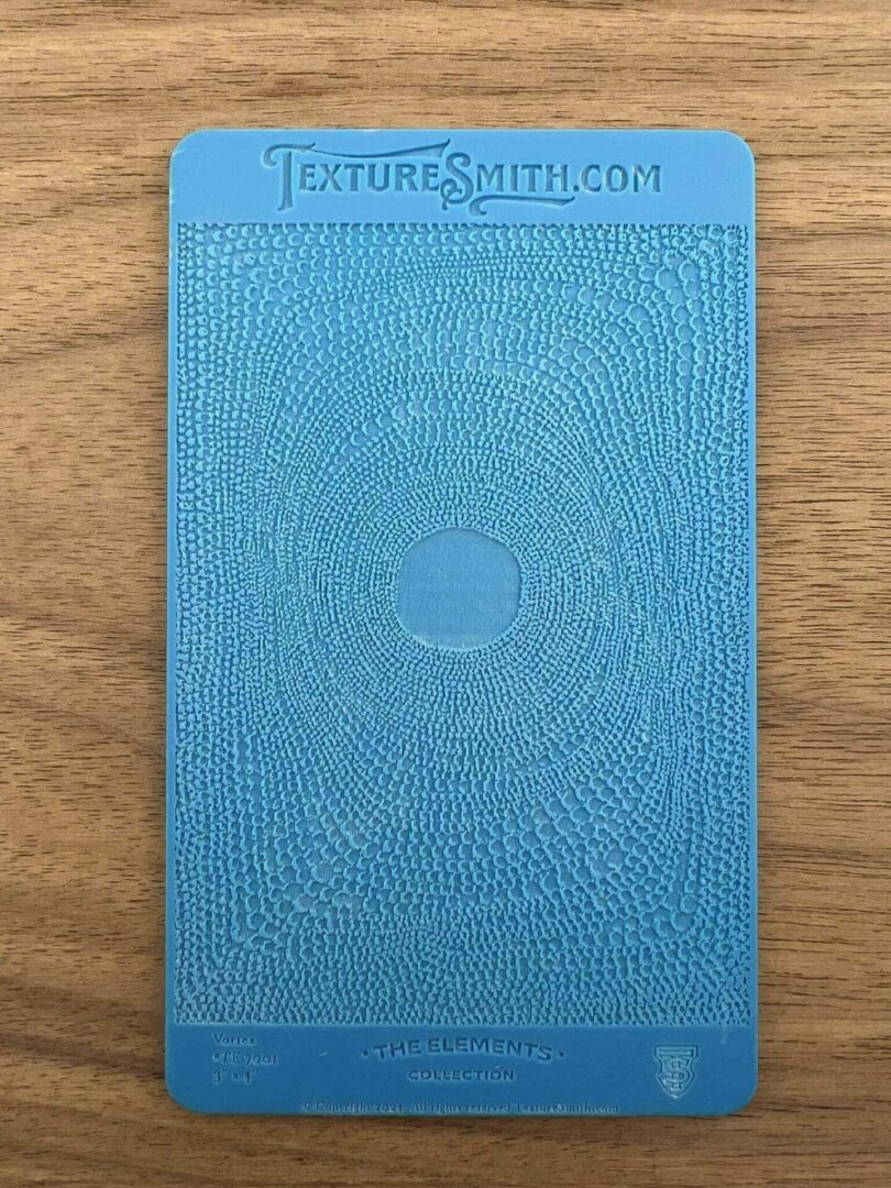Blue hardcover book with an embossed circular design on a wooden surface.