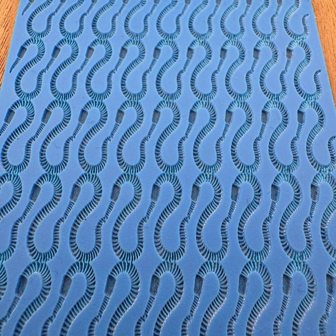 Blue fabric with repeating curved line patterns in black.