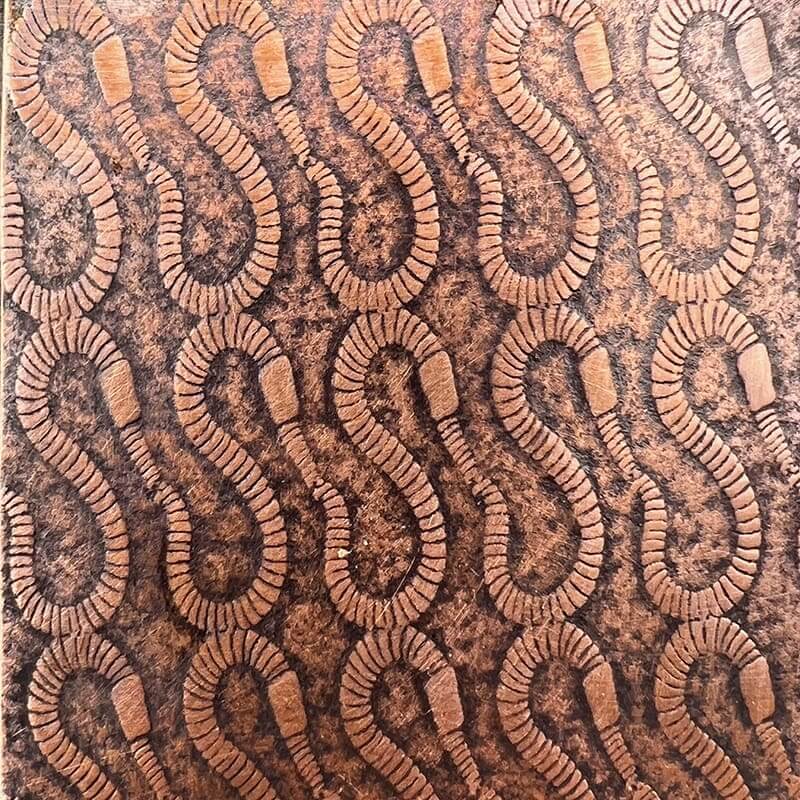 Intricate brown pattern with swirling, segmented shapes on fabric.