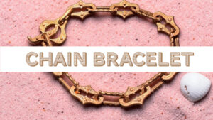 Gold chain bracelet on pink background.