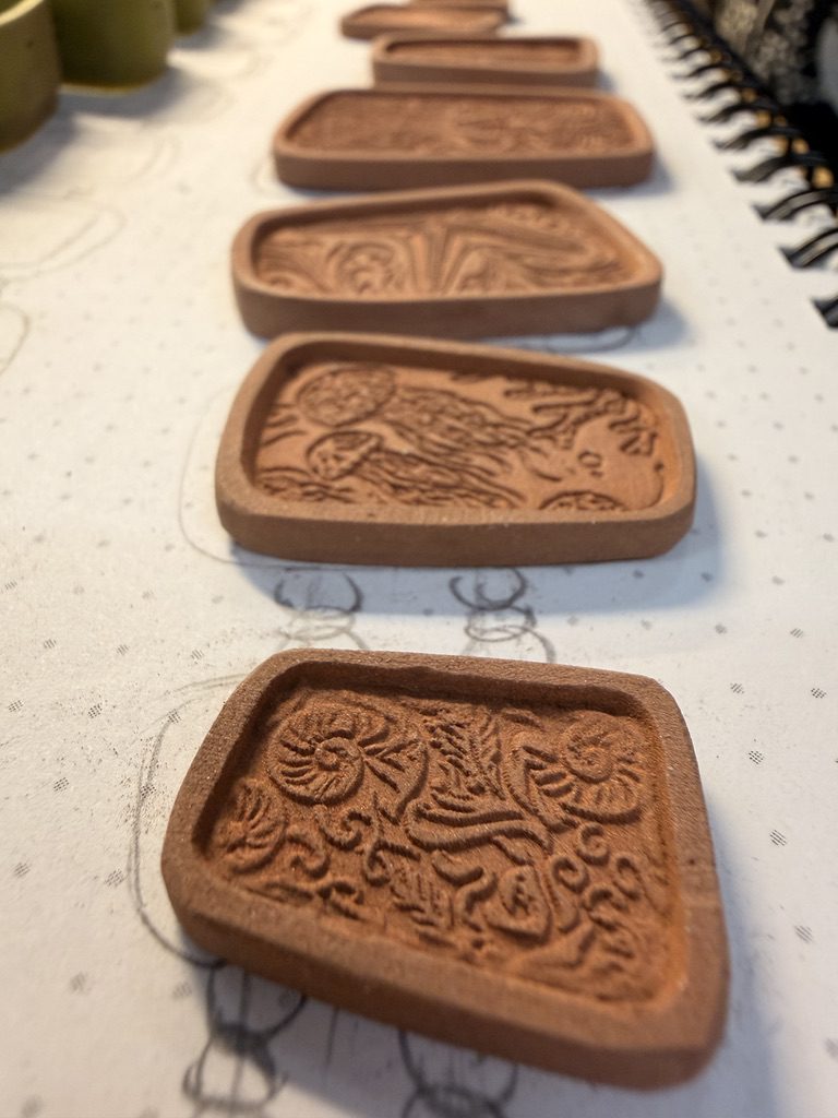 A view along the textured metal clay panels, showing their different sizes and ocean-inspired details.